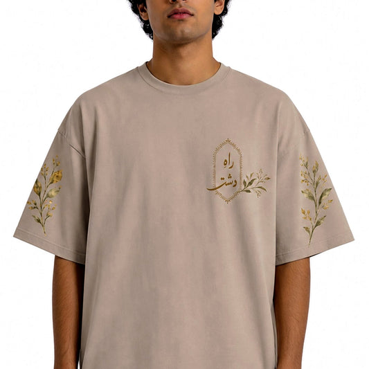 Model wearing the warm stone Raah-e-Dasht oversized botanical tee with Urdu chest emblem
