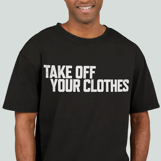 Person wearing a black acid-wash oversized T-shirt printed with TAKE OFF YOUR CLOTHES