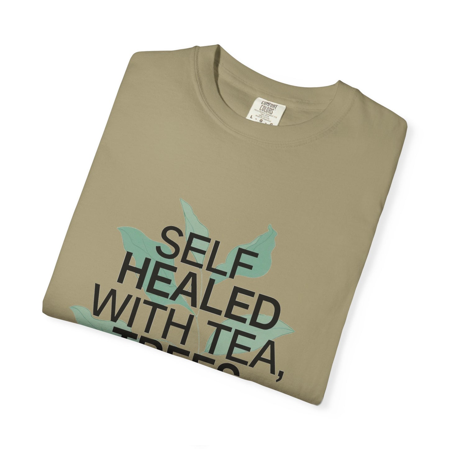 Folded khaki t-shirt with text 'SELF HEALED WITH TEA' on a white background