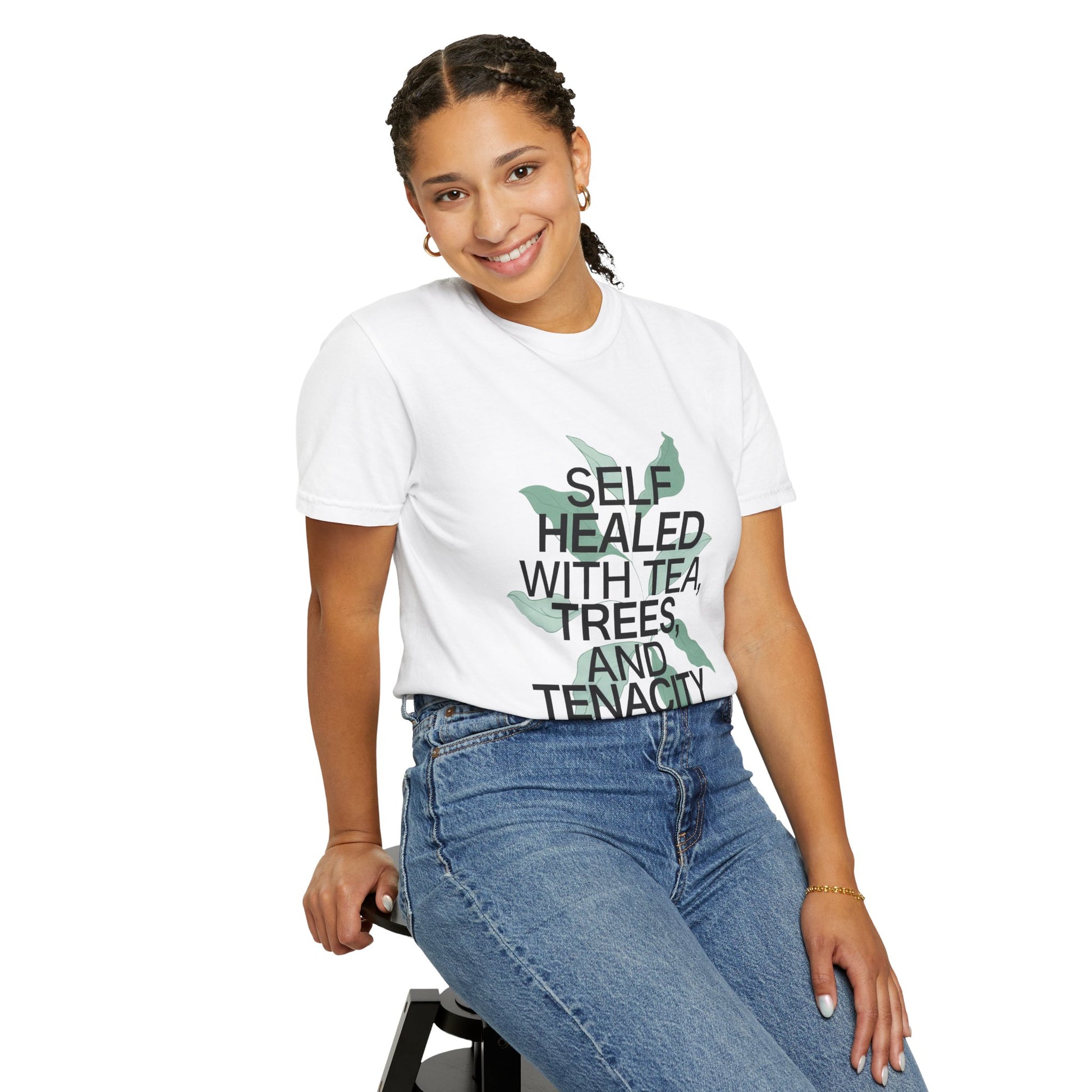 Person wearing a white t-shirt with text and graphics, sitting on a stool against a white background