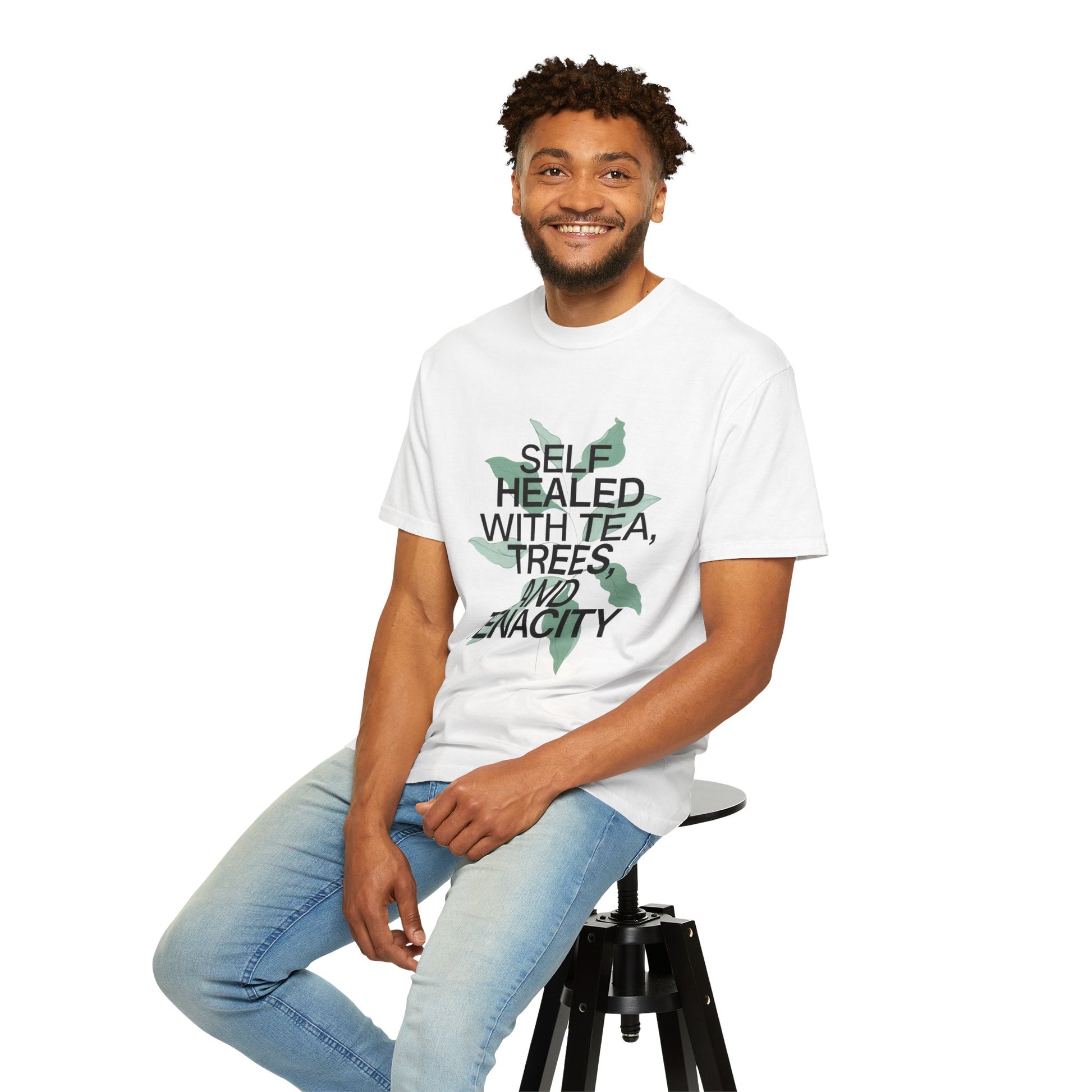 Man wearing a white t-shirt with text and graphics, sitting on a stool against a white background