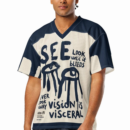 A male model wearing the Gravity of Perception conceptual streetwear jersey. The front displays raw, expressive brush-stroke lettering and dripping eye motifs on a breathable athletic mesh, designed as quiet armor for the thoughtful observer.