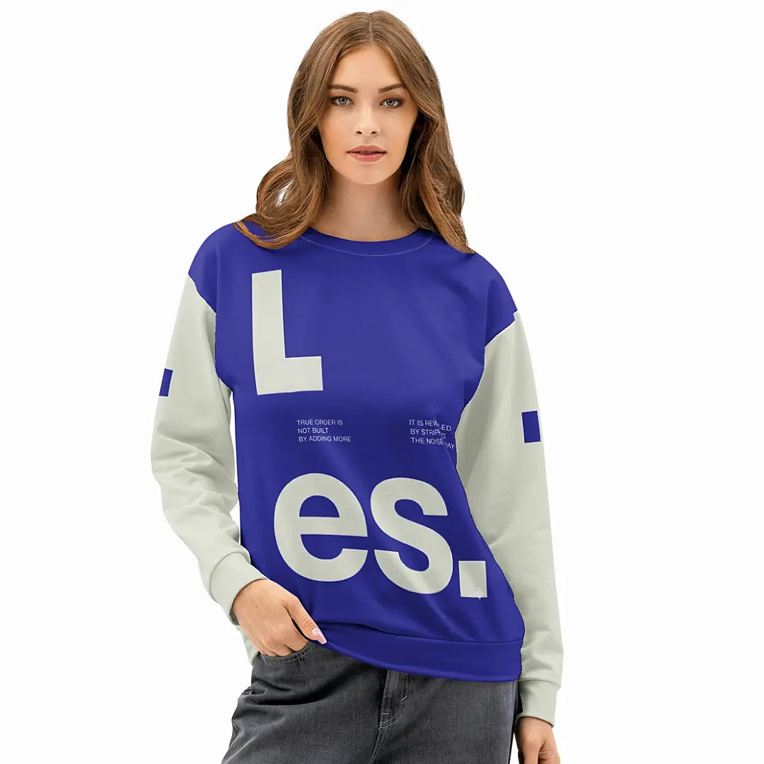 Female model wearing The Dialectic Crewneck in a relaxed fit. The image showcases the bold blue "L.es." graphic front design styled with grey wide-leg denim.