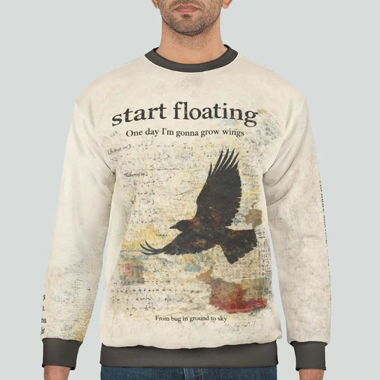 Male model wearing a dark academia raven graphic sweatshirt featuring a distressed raven in flight and vintage typography reading “Start floating”