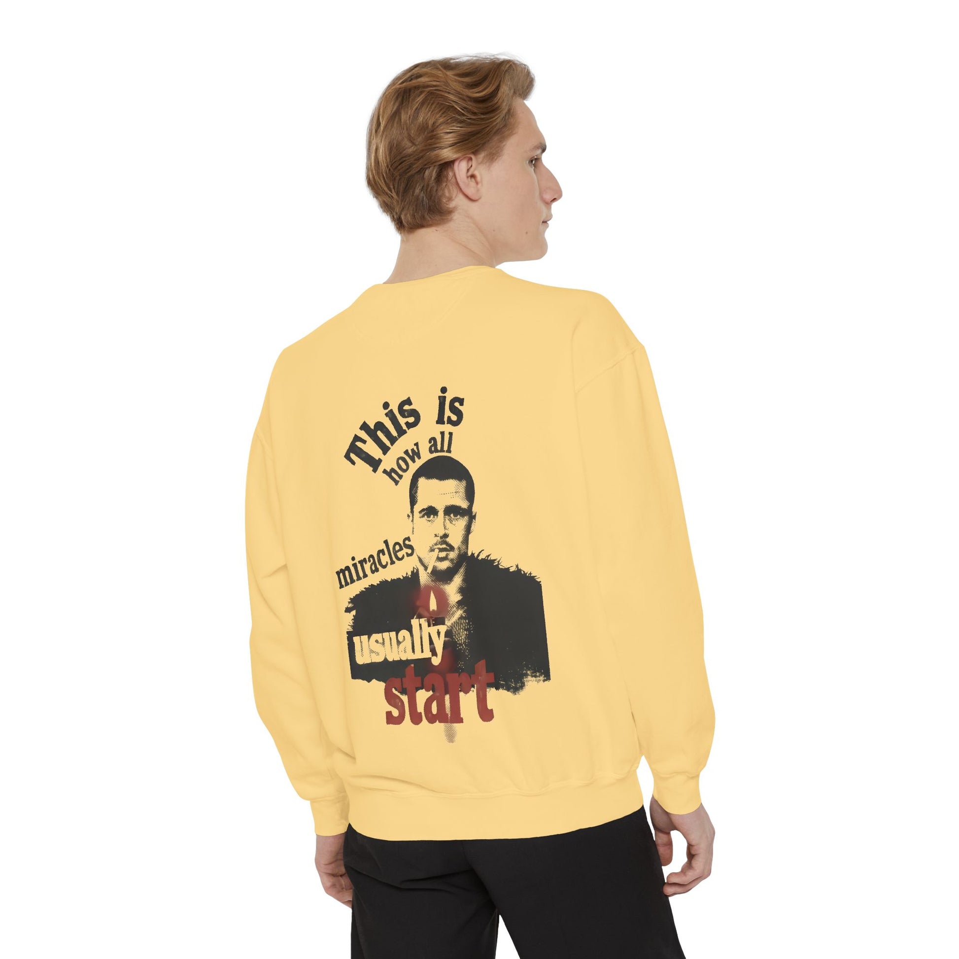 Person wearing a yellow sweatshirt with brad pitt illustration and typography "this is how all miracles usually start"