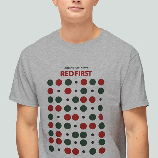 Person wearing a gray t-shirt with red and green dot pattern and text Green light needs red first