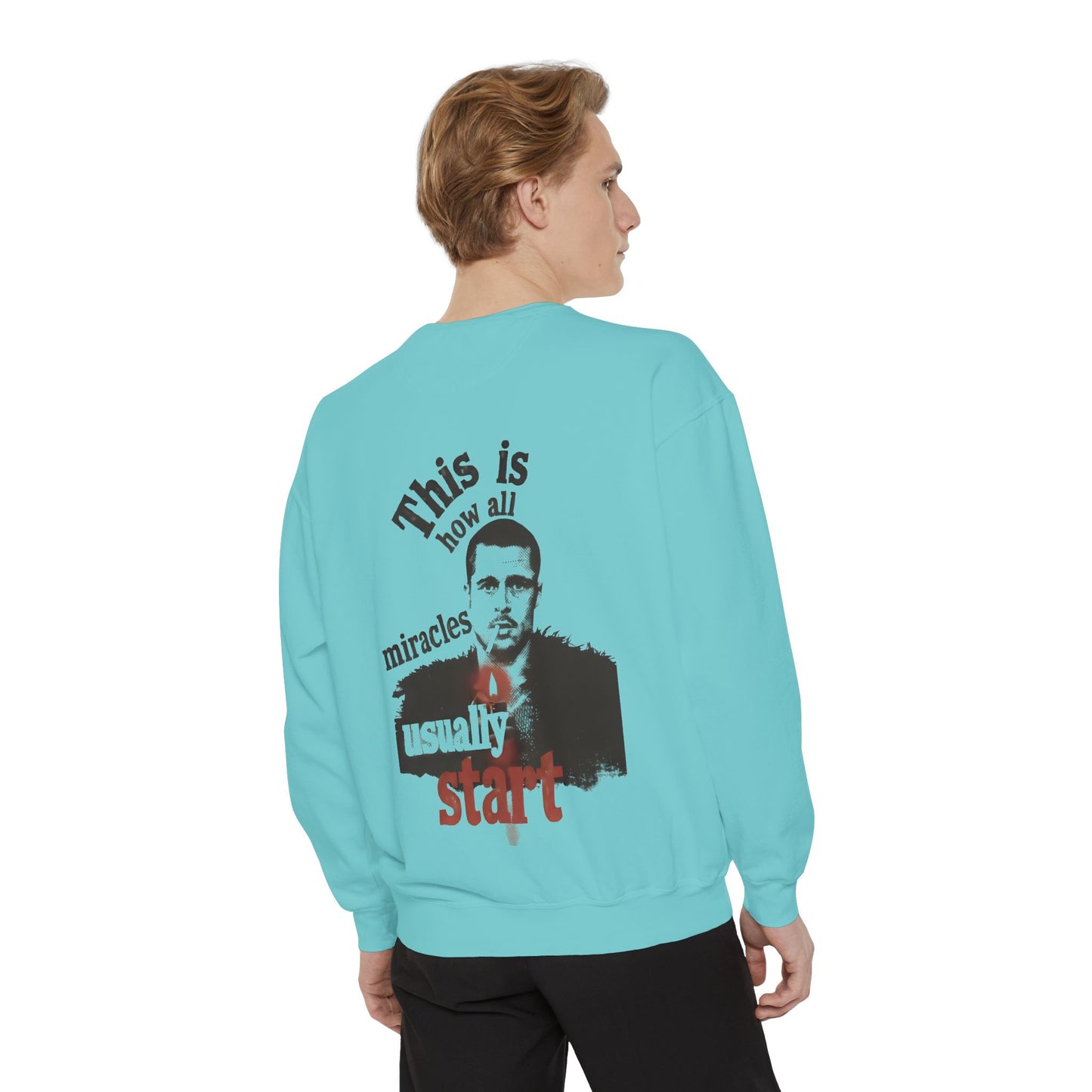 Person wearing a light blue sweatshirt with brad pitt illustration and typography "this is how all miracles usually start"