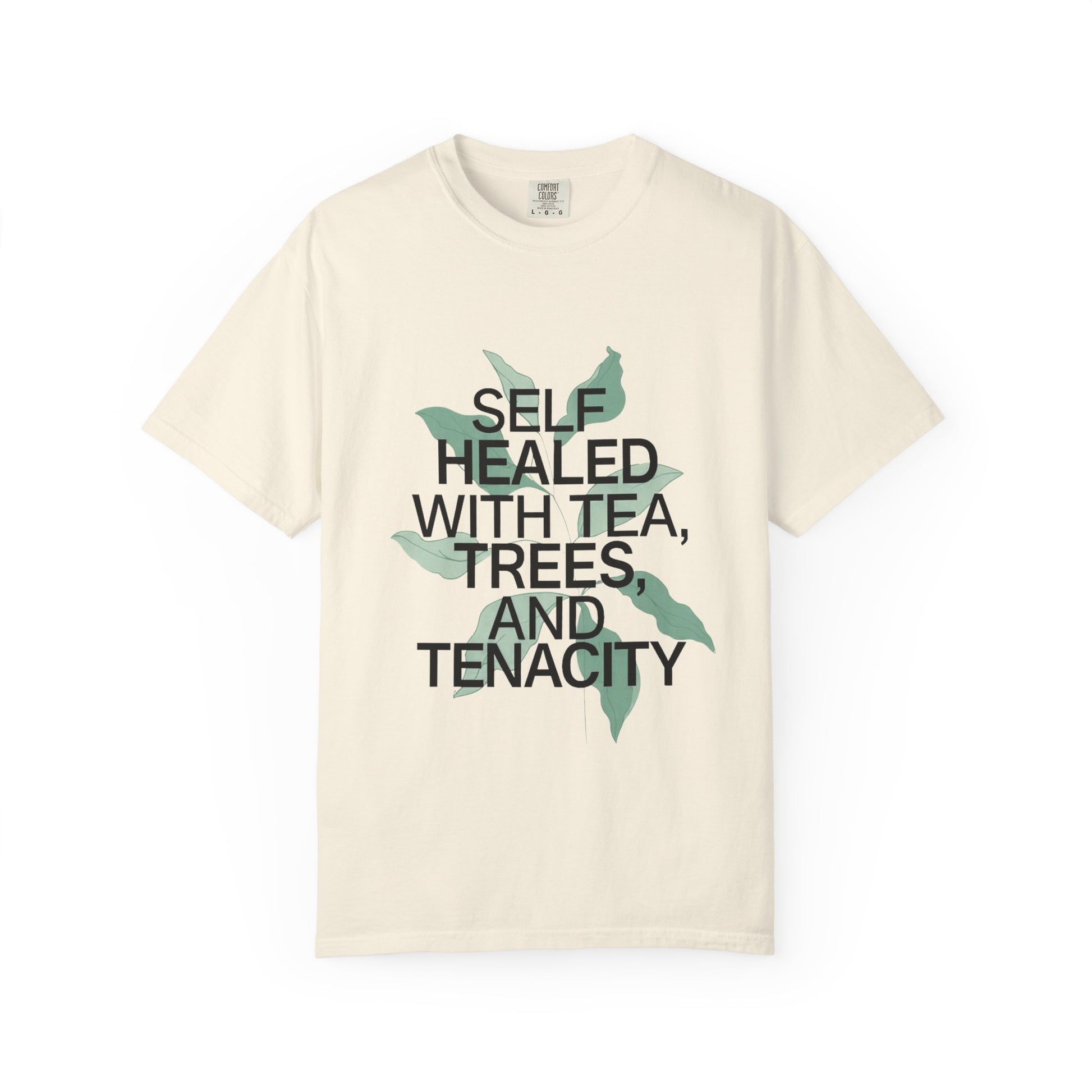 Beige t-shirt with text 'Self Healed with Tea, Trees, and Tenacity' on a white background