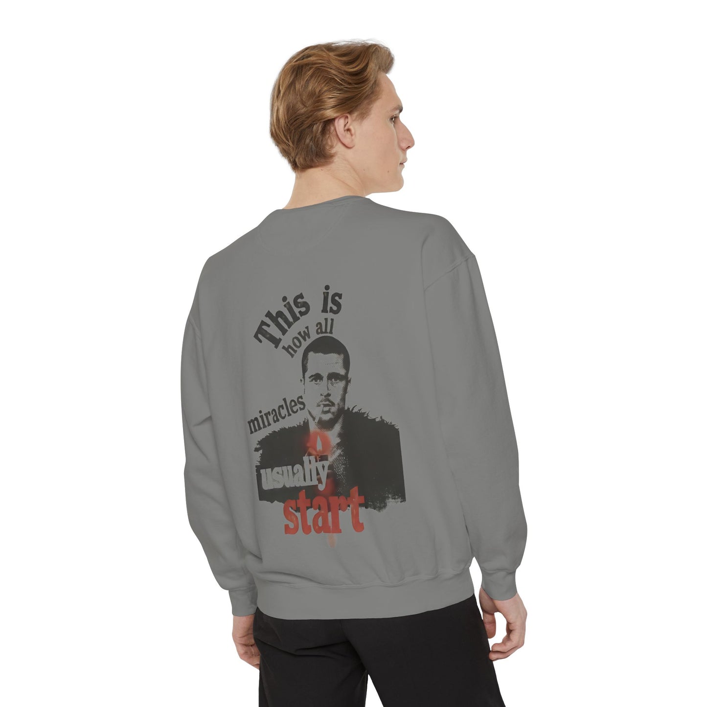 Person wearing a gray sweatshirt with a brad pitt illustration and typography "this is how all miracles usually start"