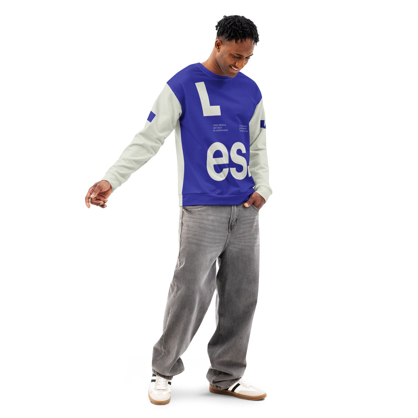 A full-body shot of a male model in a dynamic, walking pose wearing the Dialectic Crewneck. The view highlights the deep blue minimalist front panel with its architectural white "L.es." typography, paired with cream-colored sleeves and relaxed-fit grey denim jeans.