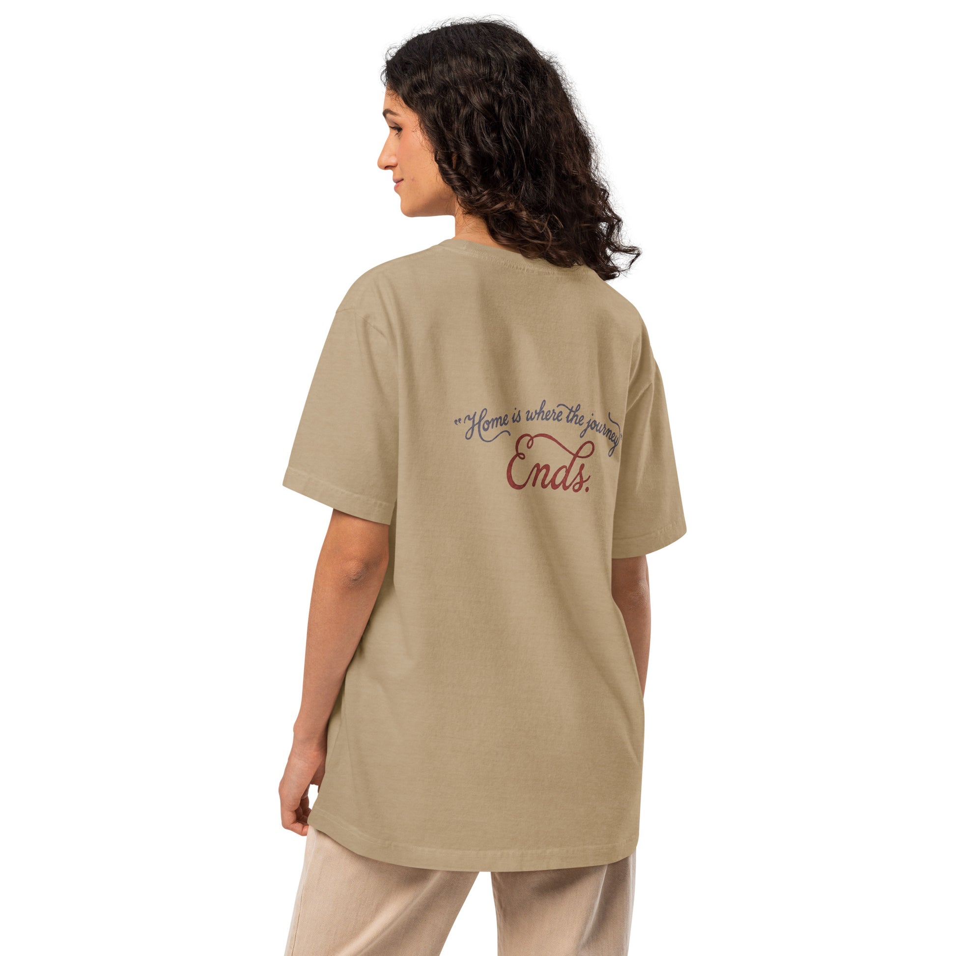 Back view of a model wearing a beige heavyweight streetwear T-shirt with a small distressed script graphic reading “Home is where the journey ends,” shown in an oversized unisex fit.
