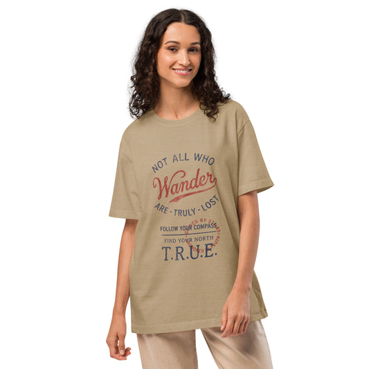 Model wearing a beige heavyweight streetwear T-shirt with a vintage distressed compass graphic and the text “Not All Who Wander Are Truly Lost,” featuring an oversized unisex fit and garment-dyed look.