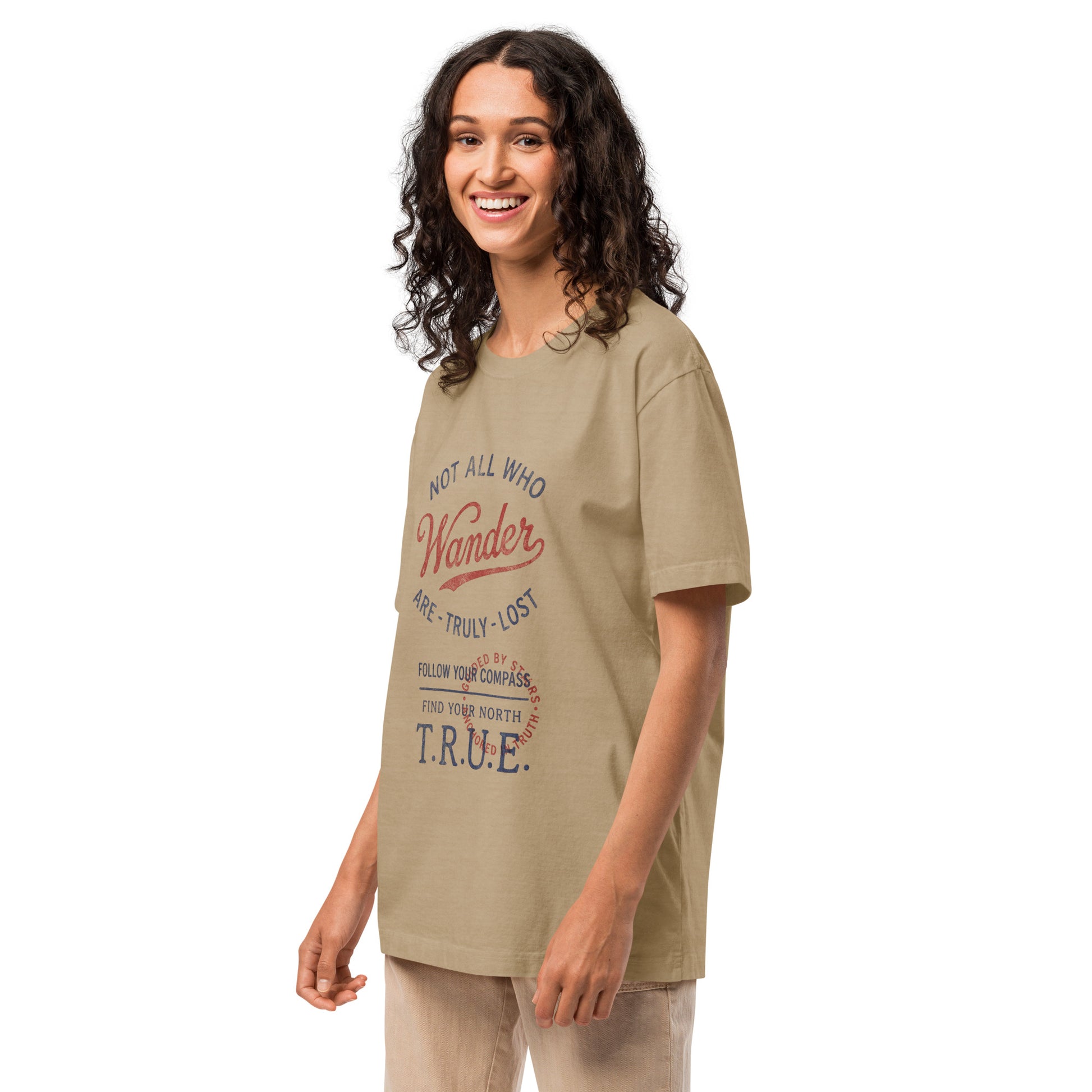 Angled front view of a model wearing a beige heavyweight streetwear T-shirt with a distressed vintage compass “Not All Who Wander Are Truly Lost” graphic, featuring an oversized unisex fit and garment-dyed finish.