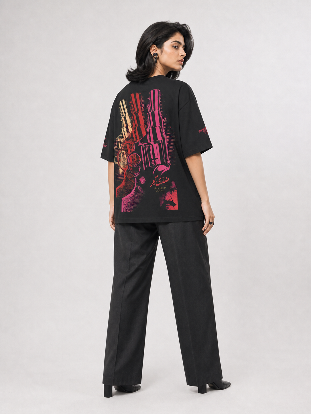Female model wearing Ziddi Gujjar black oversized tee, back revolver graphic
